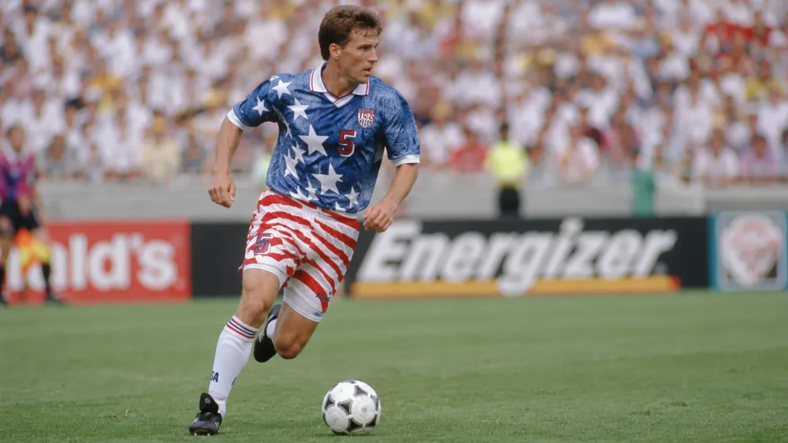 An American soccer player running on the pitch wearing the iconic 1994 starry faux-denim US national team jersey.
