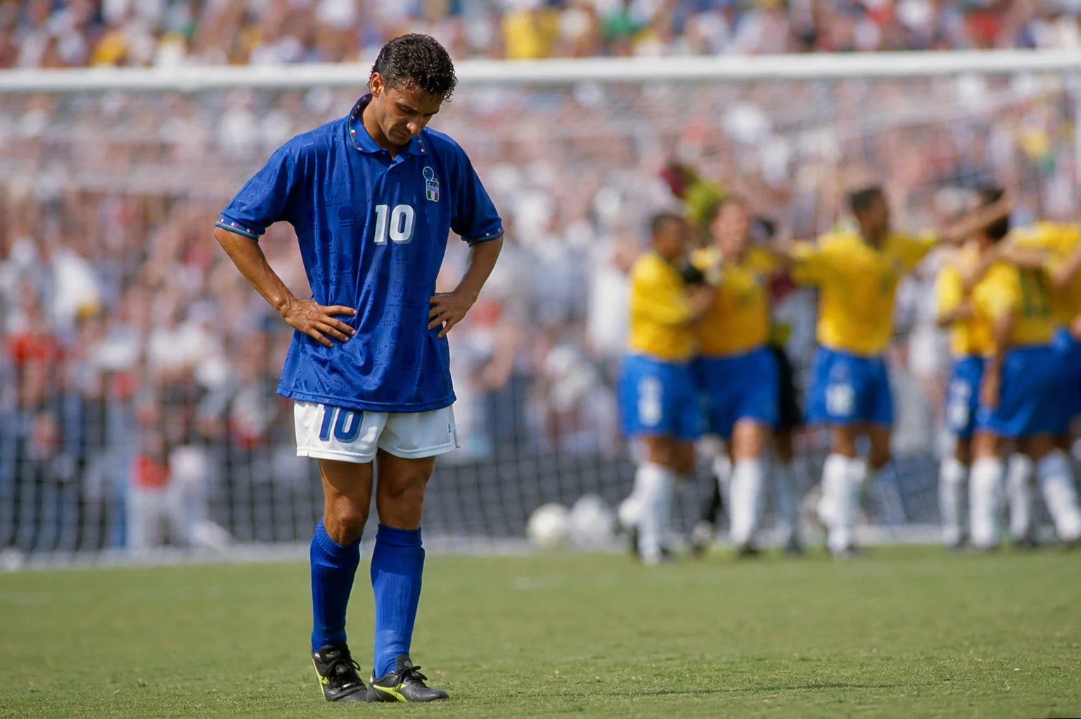 A poignant close-up of Italian footballer Roberto Baggio standing with hands on hips, head down, after blazing his decisive penalty kick over the crossbar at the sunlit Rose Bowl during the 1994 World Cup Final, handing Brazil the victory.