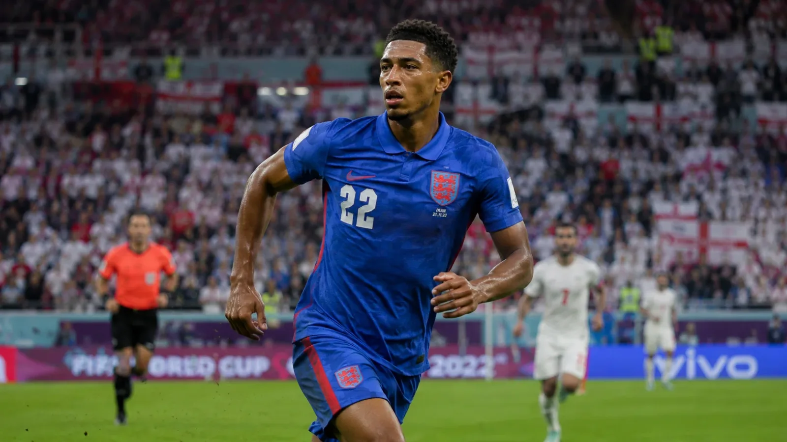 Dynamic action shot of Jude Bellingham sprinting and commanding the midfield in an England kit during a World Cup match.