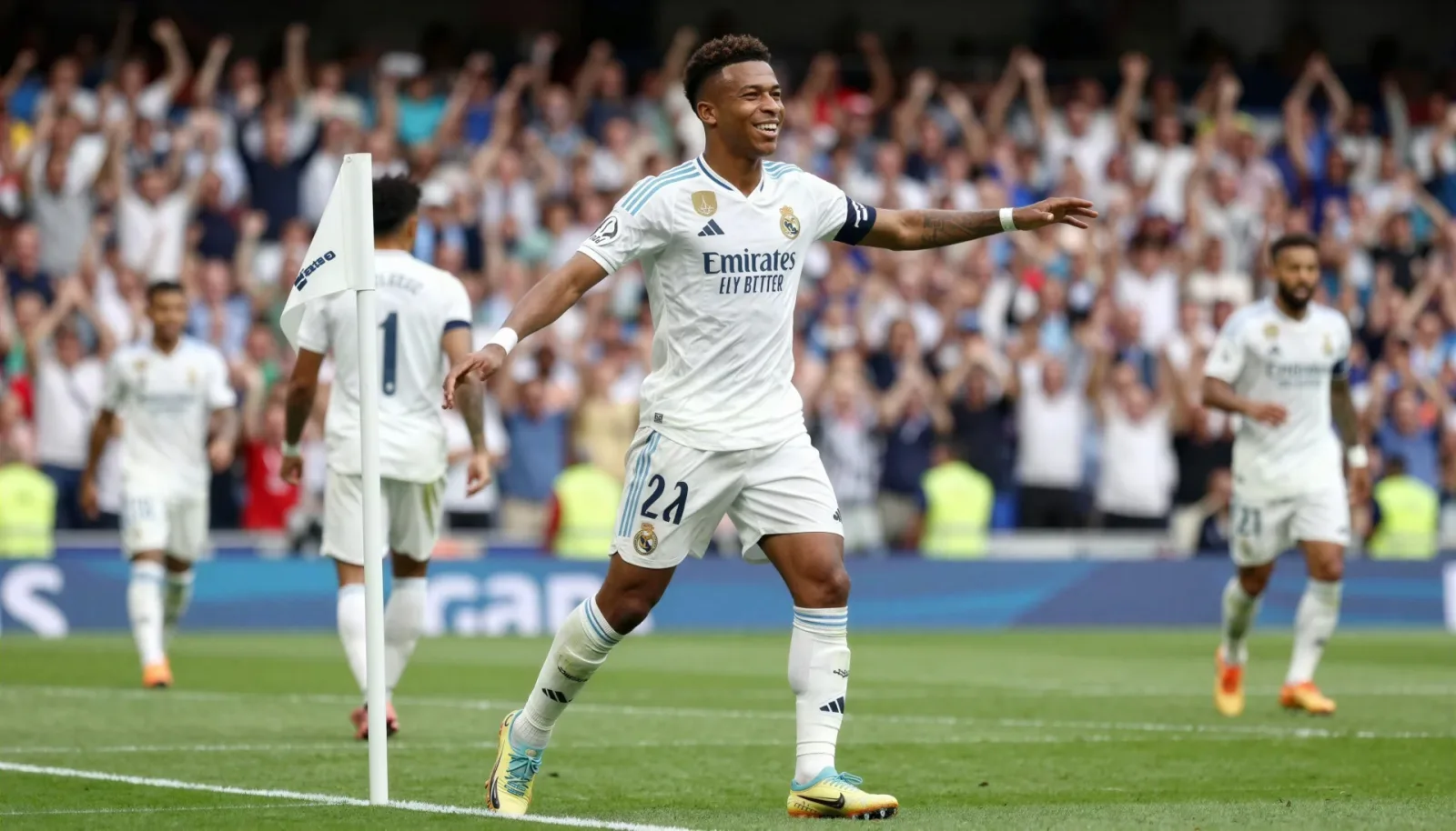 Wide shot of Vinicius Jr dancing at the corner flag to celebrate a goal, evoking Brazilian flair.