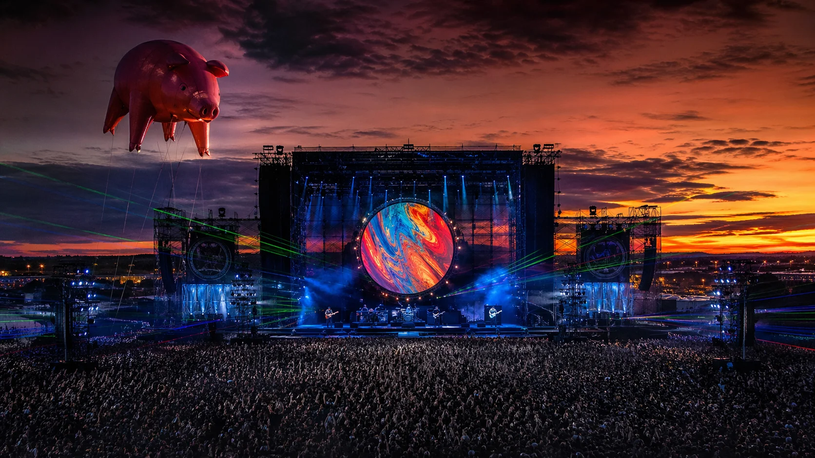 A high-quality photo from Pink Floyd's 1980 The Wall tour, showing the massive white wall under construction during the concert with towering inflatables.