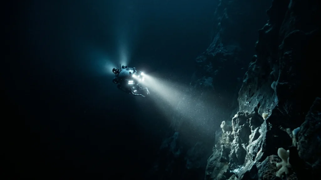 A tiny deep-sea submersible shining a bright light into the pitch-black abyss of the Mariana Trench.