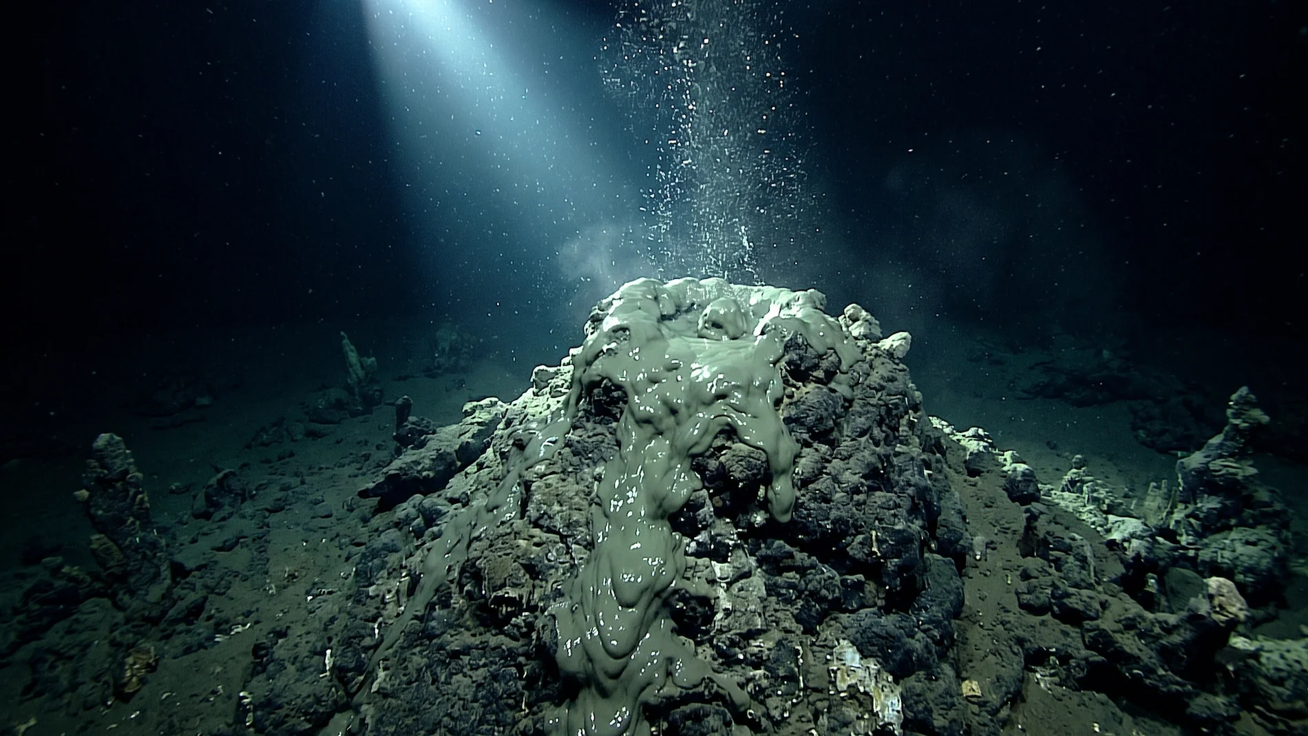 Deep-sea photo of a serpentine mud volcano erupting mineral-rich mud on the floor of the Mariana Trench.